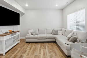 Living room with light wood finished floors and recessed lighting