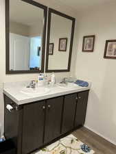 Bathroom featuring double vanity and dark wood-type flooring