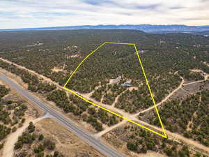 Aerial view of sparsely populated area featuring property boundaries highlighted and a mountainous background