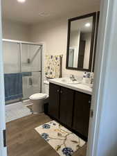 Full bath featuring double vanity, dark wood-style flooring, a stall shower, and recessed lighting