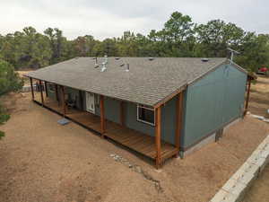 Rear view of house featuring a shingled roof and a porch