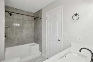 Full bath featuring vanity, a shower, and light marble finish flooring