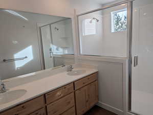 Bathroom with a stall shower, double vanity, and dark wood-style flooring