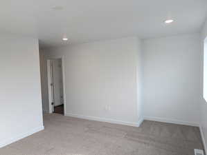 Carpeted empty room featuring baseboards and recessed lighting
