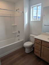 Bathroom with vanity, dark wood finished floors, and washtub / shower combination