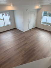Empty room featuring healthy amount of natural light, a textured ceiling, and wood finished floors