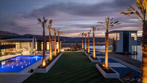Pool at dusk featuring a patio, an outdoor living space with a fire pit, and a water and mountain view