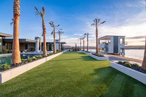 View of green lawn featuring a water view, an outdoor pool, and a patio