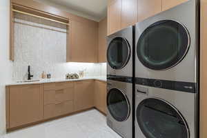 Laundry room featuring estacked washer and dryer, light tile patterned floors, and cabinet space