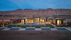 Back of property at dusk with a patio area, a mountain view, an outdoor pool, and a jacuzzi