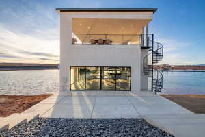 Back of house with a water view, a patio, stairway, and stucco siding