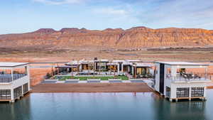 Back of property with a water and mountain view and a patio