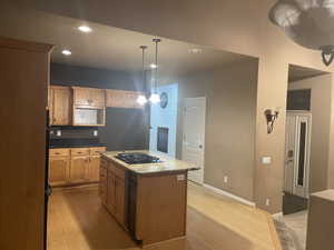 Kitchen with recessed lighting, light wood-style flooring, pendant lighting, a center island, and dark stone countertops