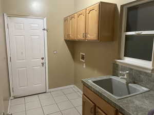 Laundry area with washer hookup, light tile patterned floors, and cabinet space