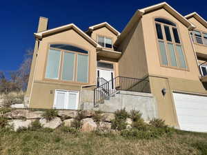 View of front of house featuring stucco siding and a chimney