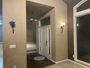 Hall featuring a chandelier and dark tile patterned flooring