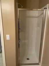 Full bathroom featuring a shower stall and wood finished floors