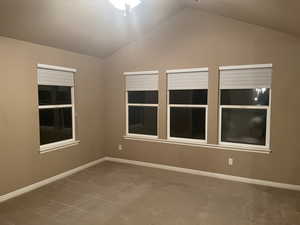 Empty room featuring vaulted ceiling and carpet flooring