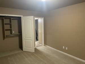 Unfurnished bedroom featuring light carpet and a closet