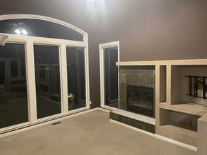 Unfurnished living room with a tiled fireplace and carpet floors