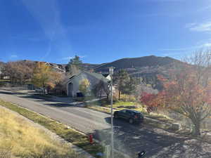 View of asphalt road featuring a mountain view, street lighting, and curbs