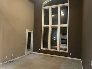 Unfurnished room featuring a towering ceiling and carpet
