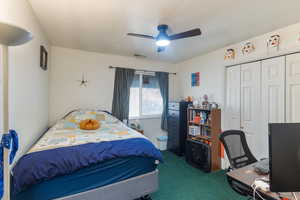 Bedroom featuring dark colored carpet, an office area, a ceiling fan, a textured ceiling, and a closet
