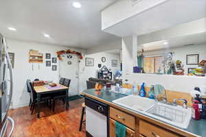 Kitchen featuring brown cabinetry, recessed lighting, freestanding refrigerator, dark wood-style floors, and white dishwasher