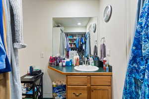 Bathroom featuring vanity, curtained shower, and a spacious closet