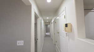 Hall with recessed lighting and light colored carpet