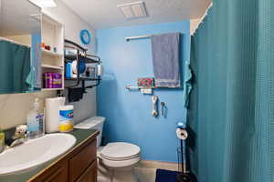 Bathroom featuring a shower with shower curtain, a textured ceiling, vanity, and tile patterned flooring