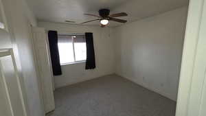 Carpeted empty room featuring ceiling fan and a textured ceiling