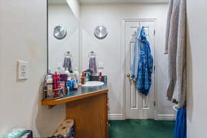 Bathroom featuring a textured wall, vanity, and carpet floors