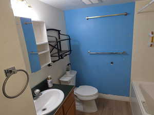 Bathroom featuring vanity, wood finished floors, shower / bathtub combination, and a textured ceiling