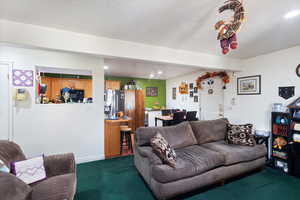 Living area featuring dark colored carpet, recessed lighting, and a textured ceiling