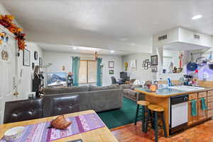 Kitchen featuring light wood-style floors, recessed lighting, a breakfast bar area, light countertops, and dishwasher