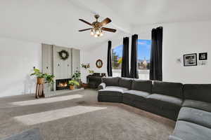 Carpeted living room with a fireplace and a ceiling fan