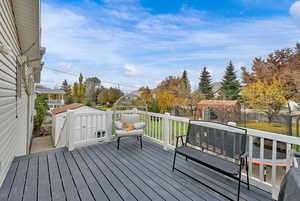 Wooden terrace featuring a storage shed and a fenced backyard