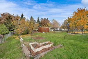 Fenced backyard with a trampoline, a vegetable garden, and an outbuilding