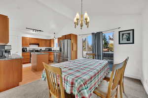 Dining space with a chandelier, light colored carpet, and high vaulted ceiling