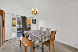 Dining space with carpet, a chandelier, and high vaulted ceiling