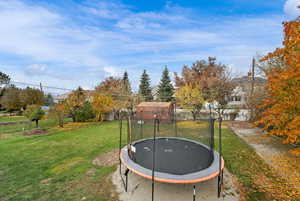 View of grassy yard with a trampoline and a residential view
