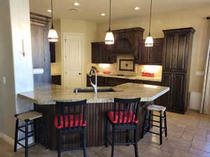 Kitchen featuring a breakfast bar, dark brown cabinets, a peninsula, hanging light fixtures, and recessed lighting