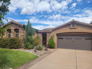 Mediterranean / spanish home featuring stone siding, a tile roof, stucco siding, and driveway