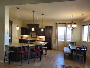 Kitchen featuring a kitchen breakfast bar, a peninsula, dark brown cabinets, backsplash, and recessed lighting