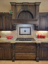 Kitchen with dark brown cabinetry, decorative backsplash, and light stone counters