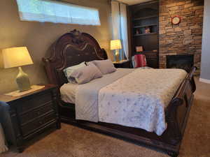 Bedroom featuring dark carpet and a fireplace