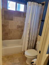 Bathroom with shower / bath combo and stone tile floors