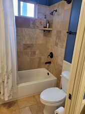 Full bathroom featuring shower / bathtub combination with curtain and toilet
