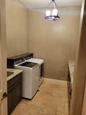 Laundry area featuring cabinet space, washer and clothes dryer, and stone tile flooring